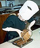 Laura Rooney Pouring the melted chocolate over the mixture in Swissroll tin